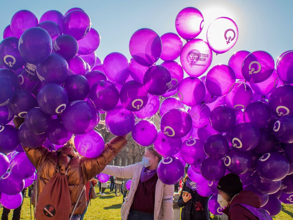 Menschen halten viele lilafarbene Luftballons